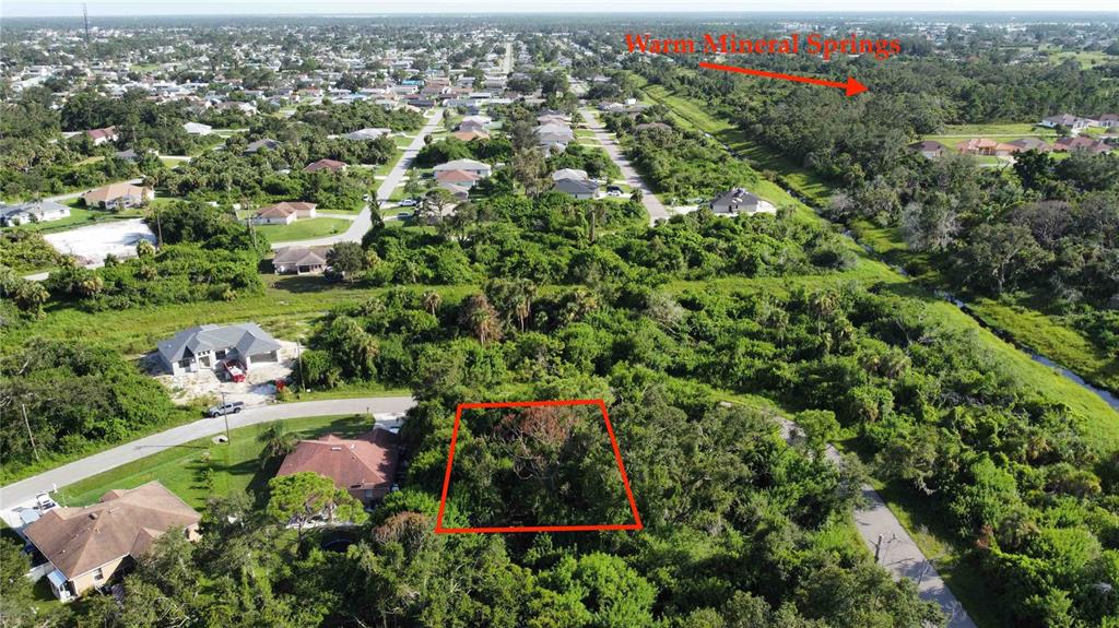 An aerial view shows a vacant, tree-covered residential lot outlined in red within a neighborhood — IRONDALE RD, NORTH PORT, FL