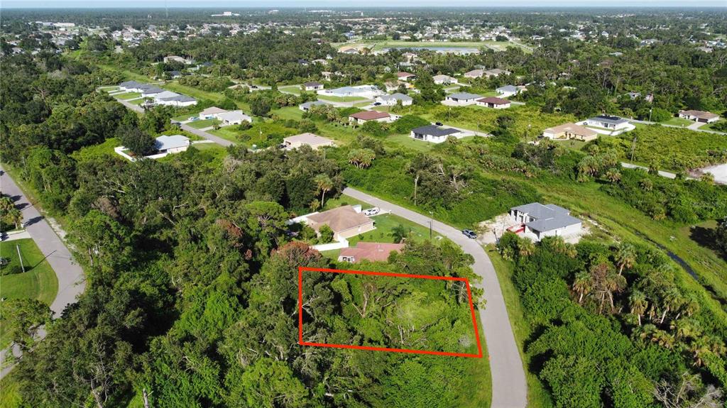 An aerial view shows a vacant, wooded residential lot outlined in red along a paved road — IRONDALE RD, NORTH PORT, FL