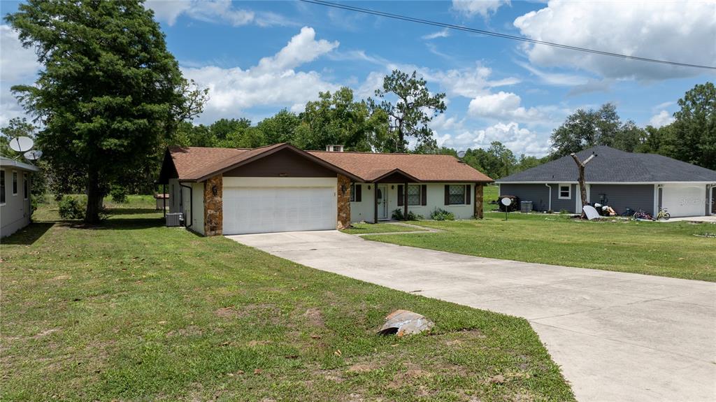 A single-story house with a white garage, brown roof, and stone accents on the front — 15191 NE 9TH STREET, WILLISTON, FL