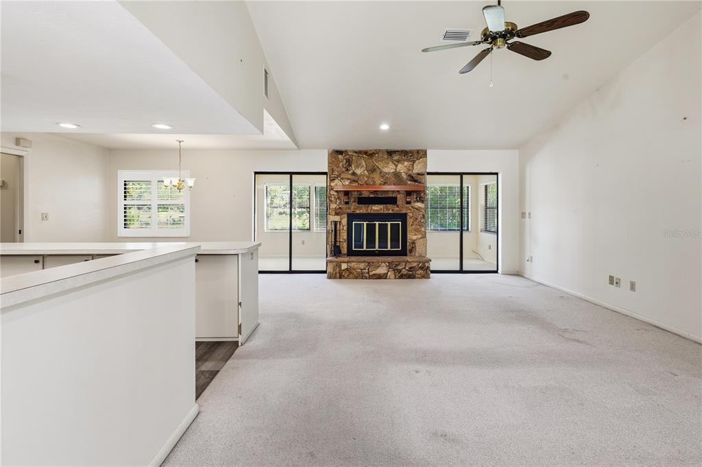A living room with a stone fireplace, carpeted flooring, and sliding glass doors — 15191 NE 9TH STREET, WILLISTON, FL