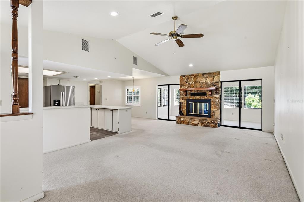 A spacious living room features a stone fireplace, vaulted ceilings, and an open kitchen area — 15191 NE 9TH STREET, WILLISTON, FL