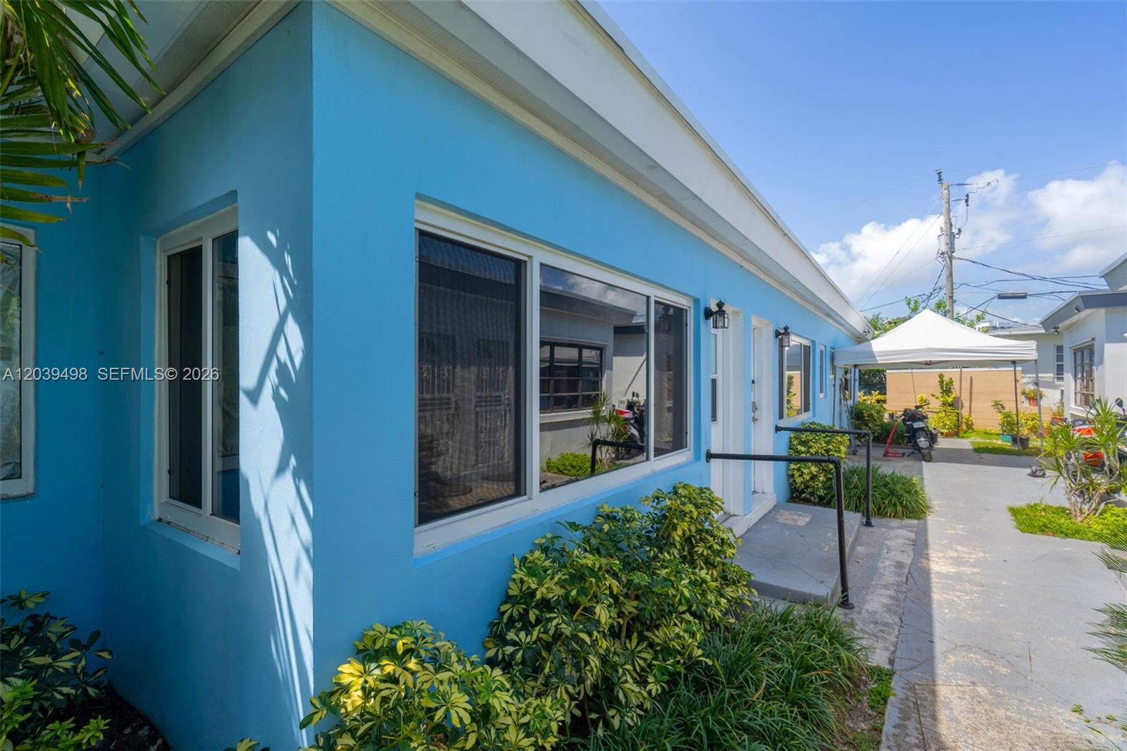 The exterior of a bright blue building features a walkway, windows, and a white canopy — 2120 Biarritz Dr, Miami Beach FL 33141, MIAMI BEACH, FL