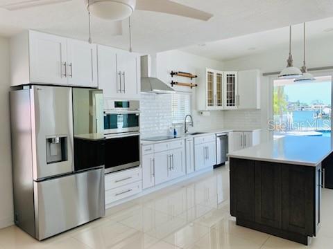 A modern kitchen features white cabinetry, stainless steel appliances, and a dark wood kitchen island — 14162 W PARSLEY DRIVE, MADEIRA BEACH, FL