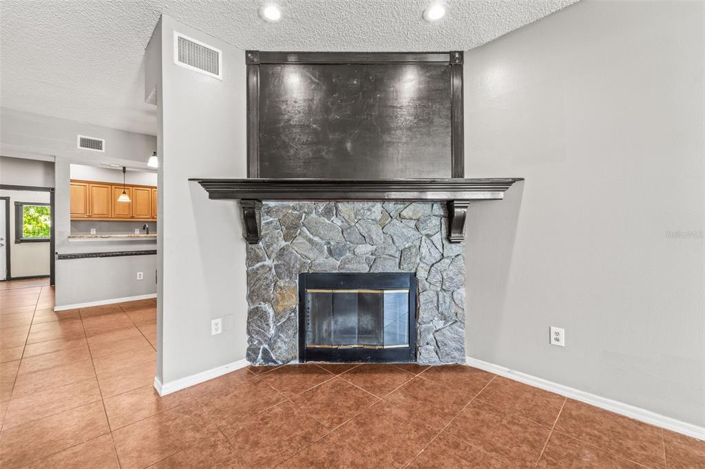 A living room features a stone fireplace with a dark wood mantel and surround — 312 WINCHESTER WAY, PALM HARBOR, FL