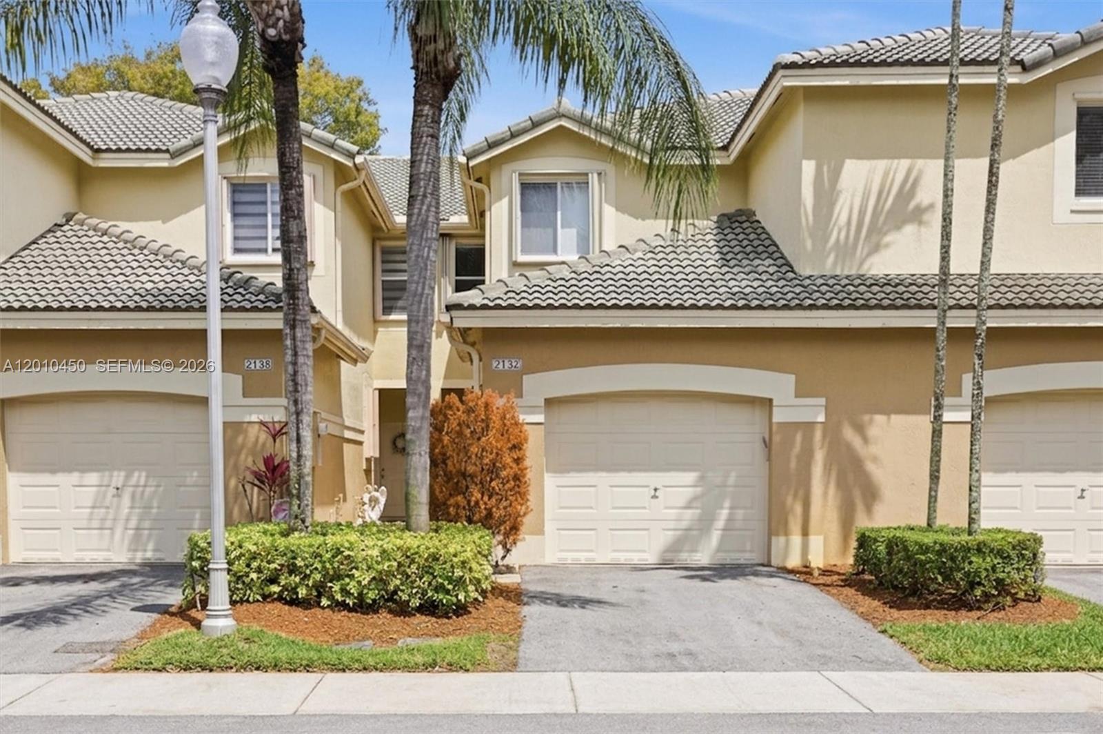 A two-story townhouse exterior features a beige stucco facade, tiled roof, and attached garages — 2132 Bahia Ln, Weston FL 33327, WESTON, FL