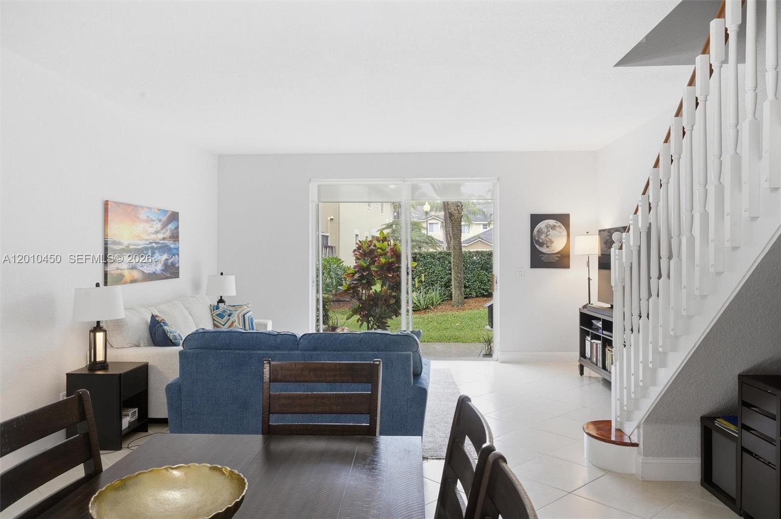 A living room with a blue sofa, dining table, and stairs leading to an upper level — 2132 Bahia Ln, Weston FL 33327, WESTON, FL