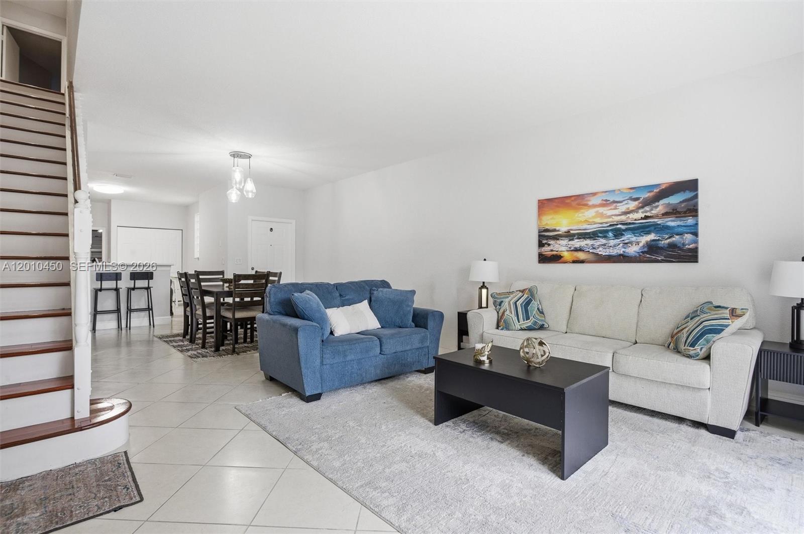 A living room features a blue loveseat, a light sofa, and a staircase — 2132 Bahia Ln, Weston FL 33327, WESTON, FL