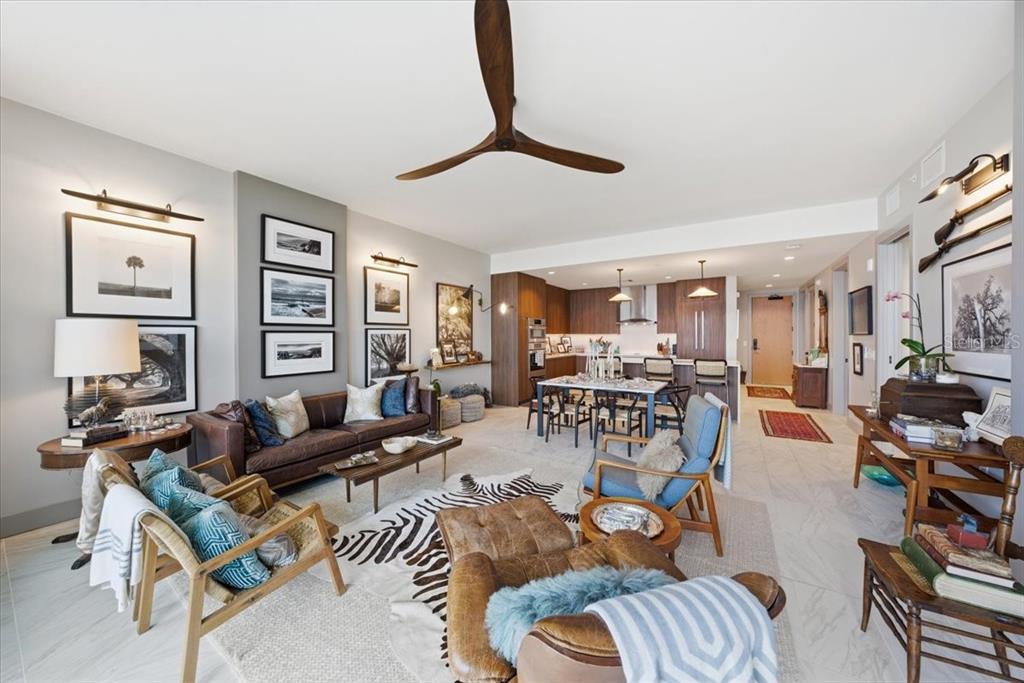 An open-concept living room and kitchen featuring a leather sofa, zebra rug, and wood cabinetry — 777 3RD AVENUE N UNIT 1606, ST PETERSBURG, FL