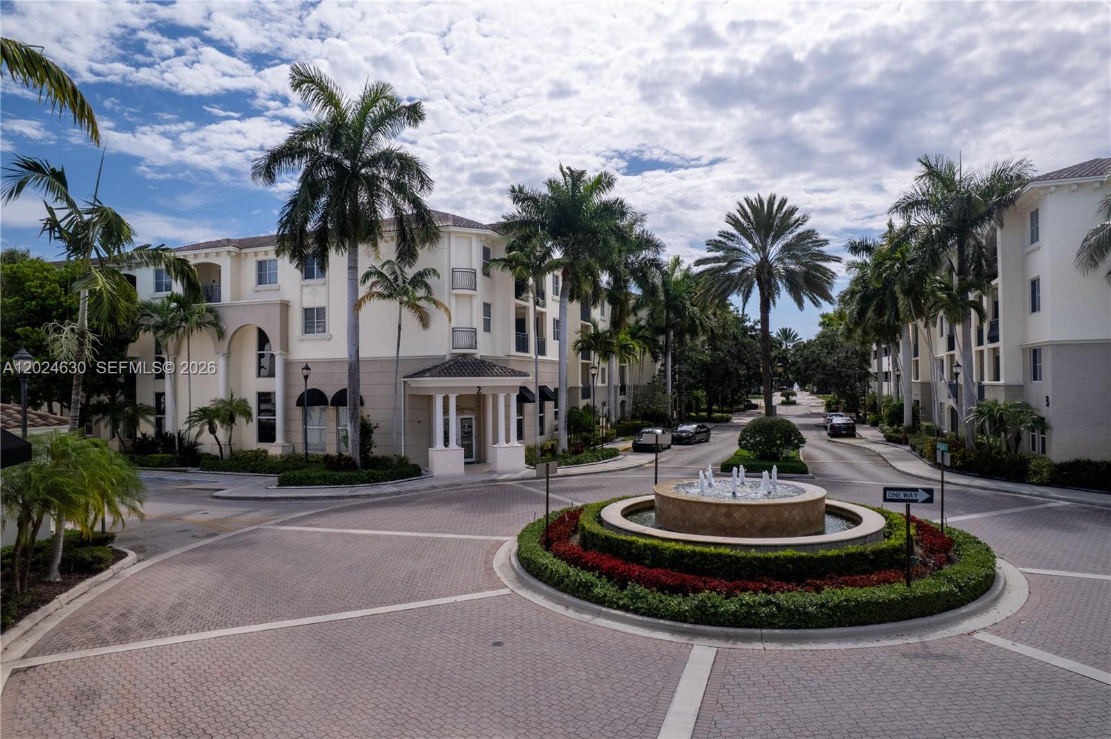 An exterior view of a multi-story apartment complex featuring a circular fountain and palm trees — 2 Renaissance Way # 305, Boynton Beach FL 33426, BOYNTON BEACH, FL