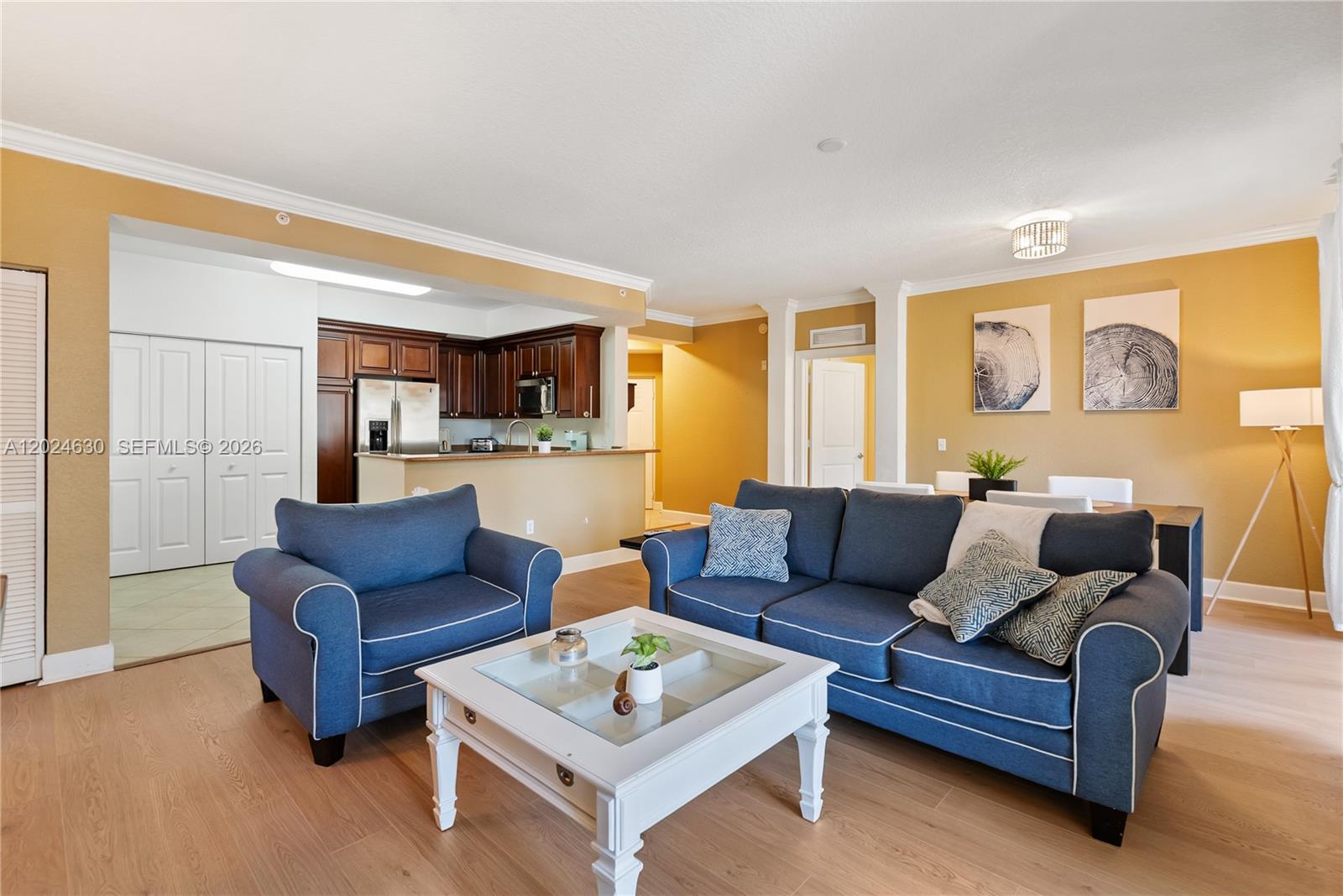 A living room features blue furniture, a white coffee table, and an open kitchen area — 2 Renaissance Way # 305, Boynton Beach FL 33426, BOYNTON BEACH, FL