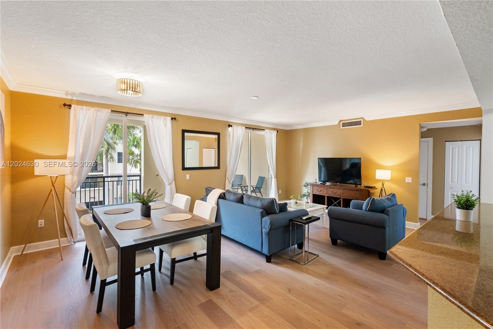 A living and dining area features yellow walls, blue furniture, and light wood flooring — 2 Renaissance Way # 305, Boynton Beach FL 33426, BOYNTON BEACH, FL