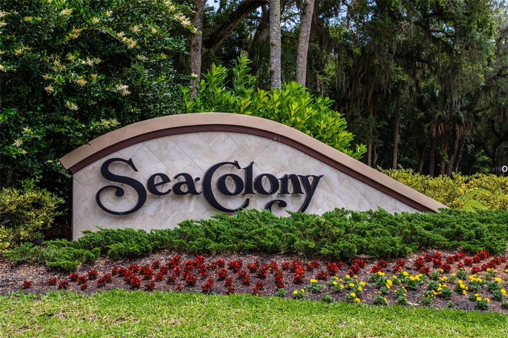 A curved stone monument sign for Sea Colony sits in a landscaped garden bed — 24 MEDFORD DRIVE, PALM COAST, FL