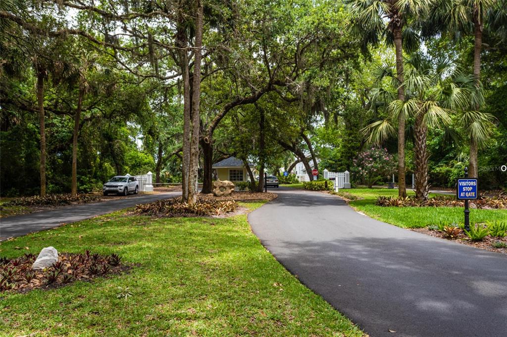A paved driveway leads to a gated residential entrance surrounded by lush trees and landscaping — 24 MEDFORD DRIVE, PALM COAST, FL