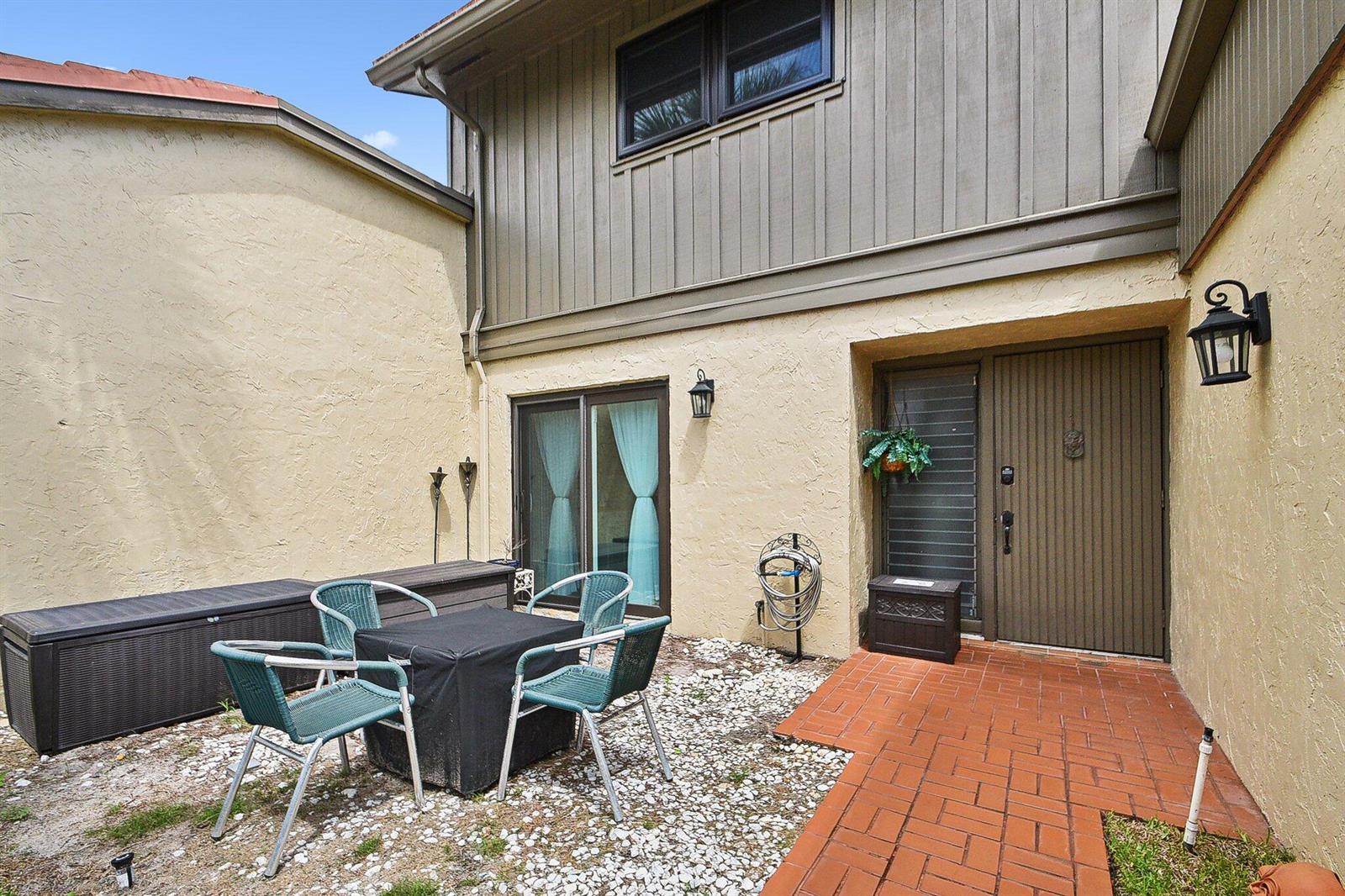 A patio area features a brick walkway, a small table with chairs, and a front door — 11063 Oakdale Road, Boynton Beach FL 33437, BOYNTON BEACH, FL