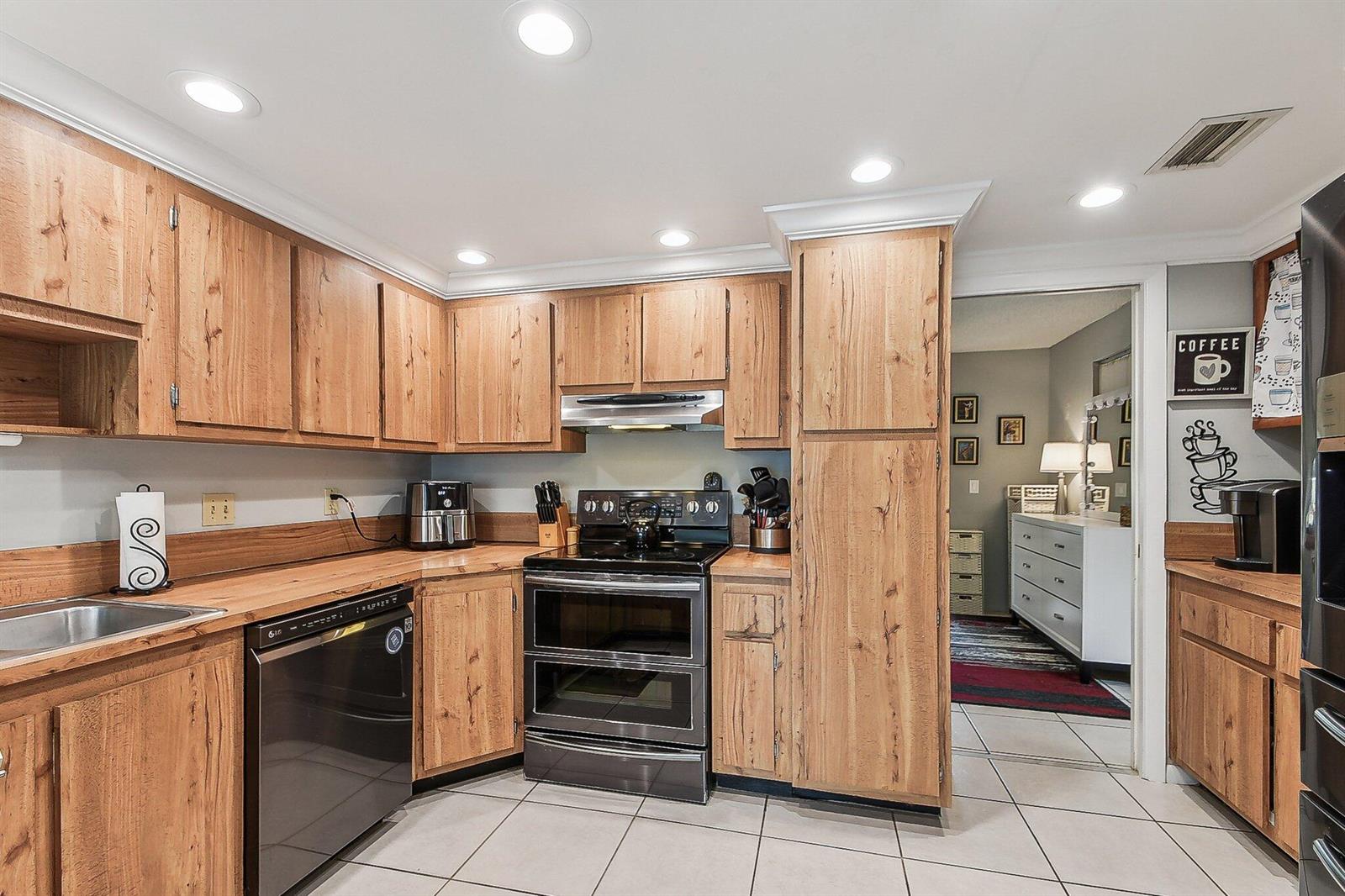 A kitchen with wood-grain cabinets, black appliances, and light-colored tile flooring — 11063 Oakdale Road, Boynton Beach FL 33437, BOYNTON BEACH, FL