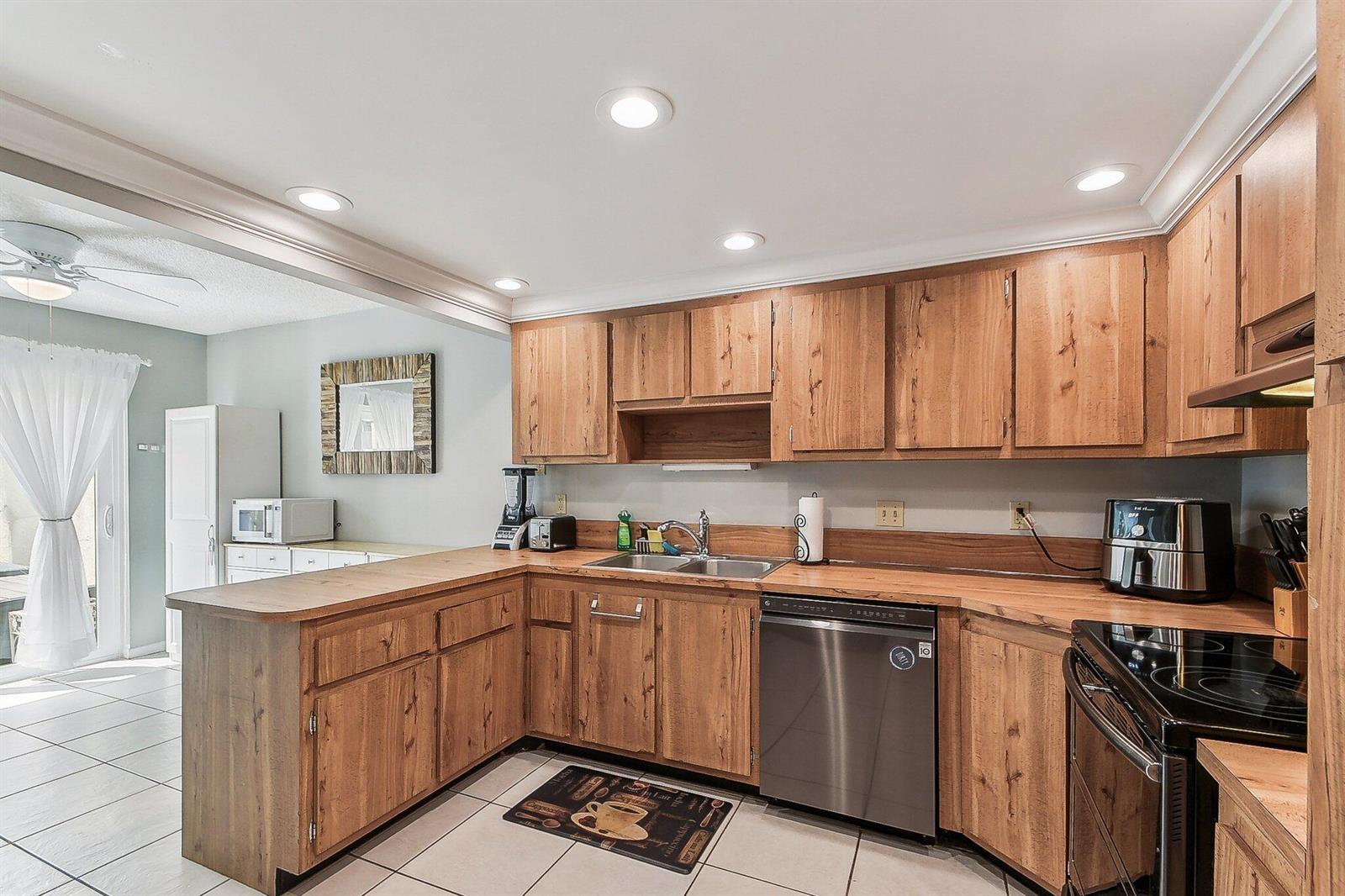 A kitchen features wood cabinets, laminate countertops, stainless steel appliances, and light-colored tile flooring — 11063 Oakdale Road, Boynton Beach FL 33437, BOYNTON BEACH, FL