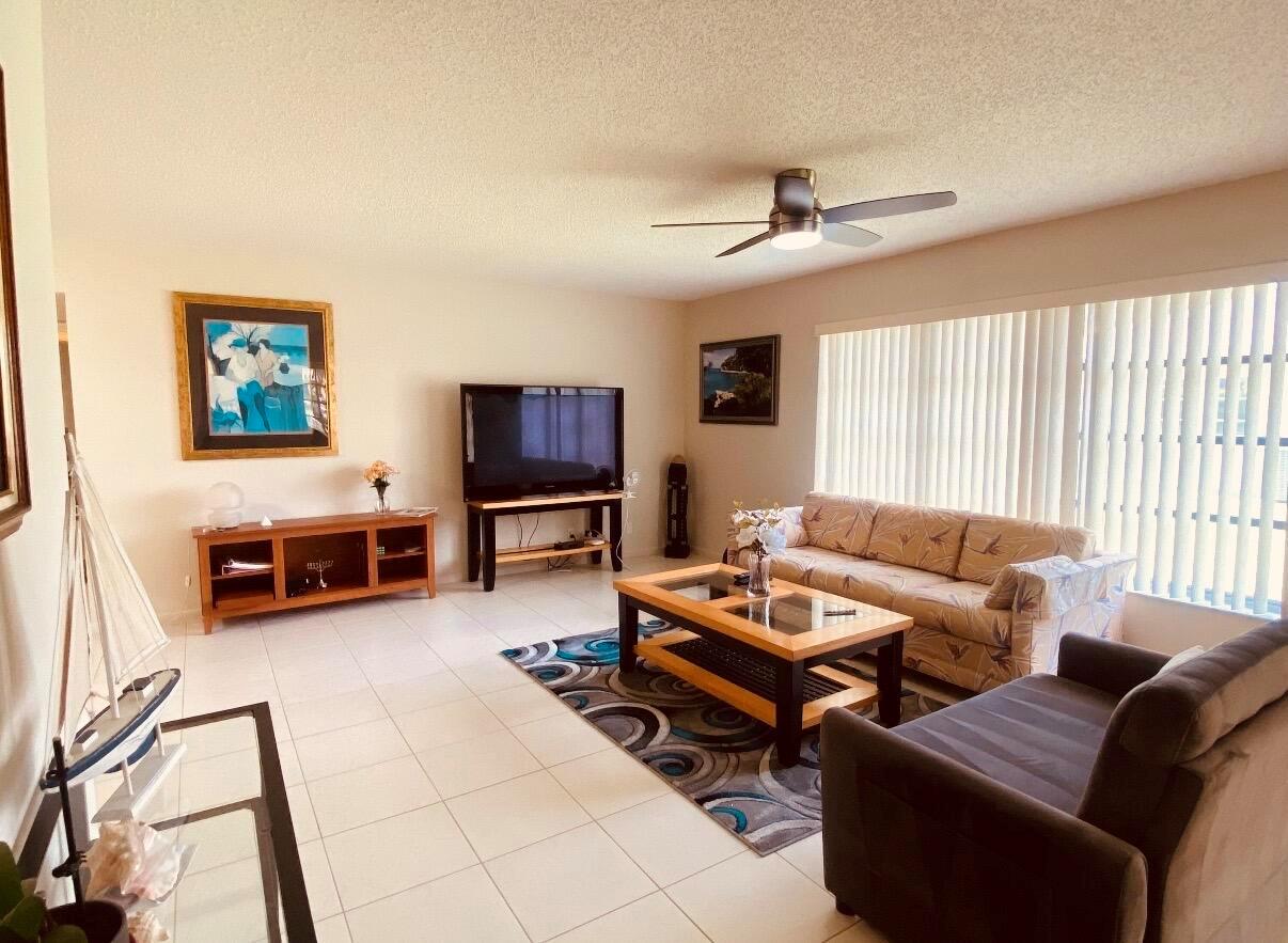 A living room with tile floors, a ceiling fan, a television, and two sofas — 5126 Lakefront Boulevard # D, Delray Beach FL 33484, DELRAY BEACH, FL