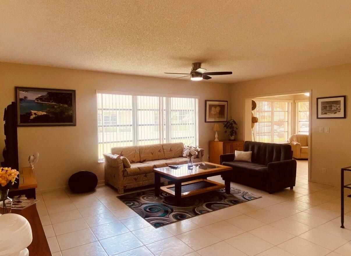A living room features tile flooring, a ceiling fan, and two sofas around a coffee table — 5126 Lakefront Boulevard # D, Delray Beach FL 33484, DELRAY BEACH, FL