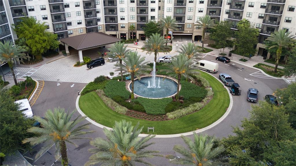 An aerial view of an apartment complex entrance featuring a circular driveway and central fountain — 14501 GROVE RESORT AVENUE UNIT 2135, WINTER GARDEN, FL