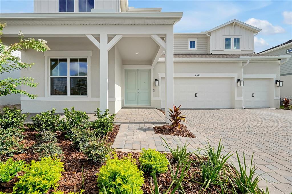 A light-colored two-story house features a paved driveway, a double-door entrance, and landscaped front gardens — 8399 PARK CLIFF WAY, ORLANDO, FL