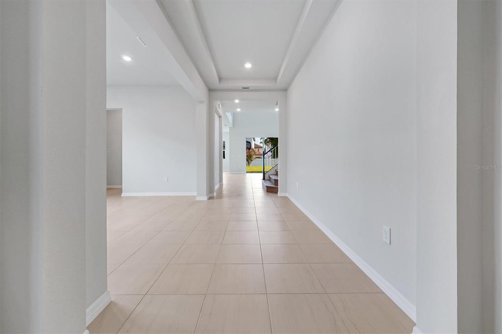 A bright, tiled hallway leads toward an open living area with a staircase in view — 8399 PARK CLIFF WAY, ORLANDO, FL