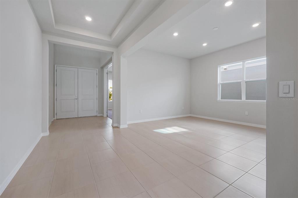 An empty room with light-colored tile flooring, recessed lighting, and a double-door entryway — 8399 PARK CLIFF WAY, ORLANDO, FL