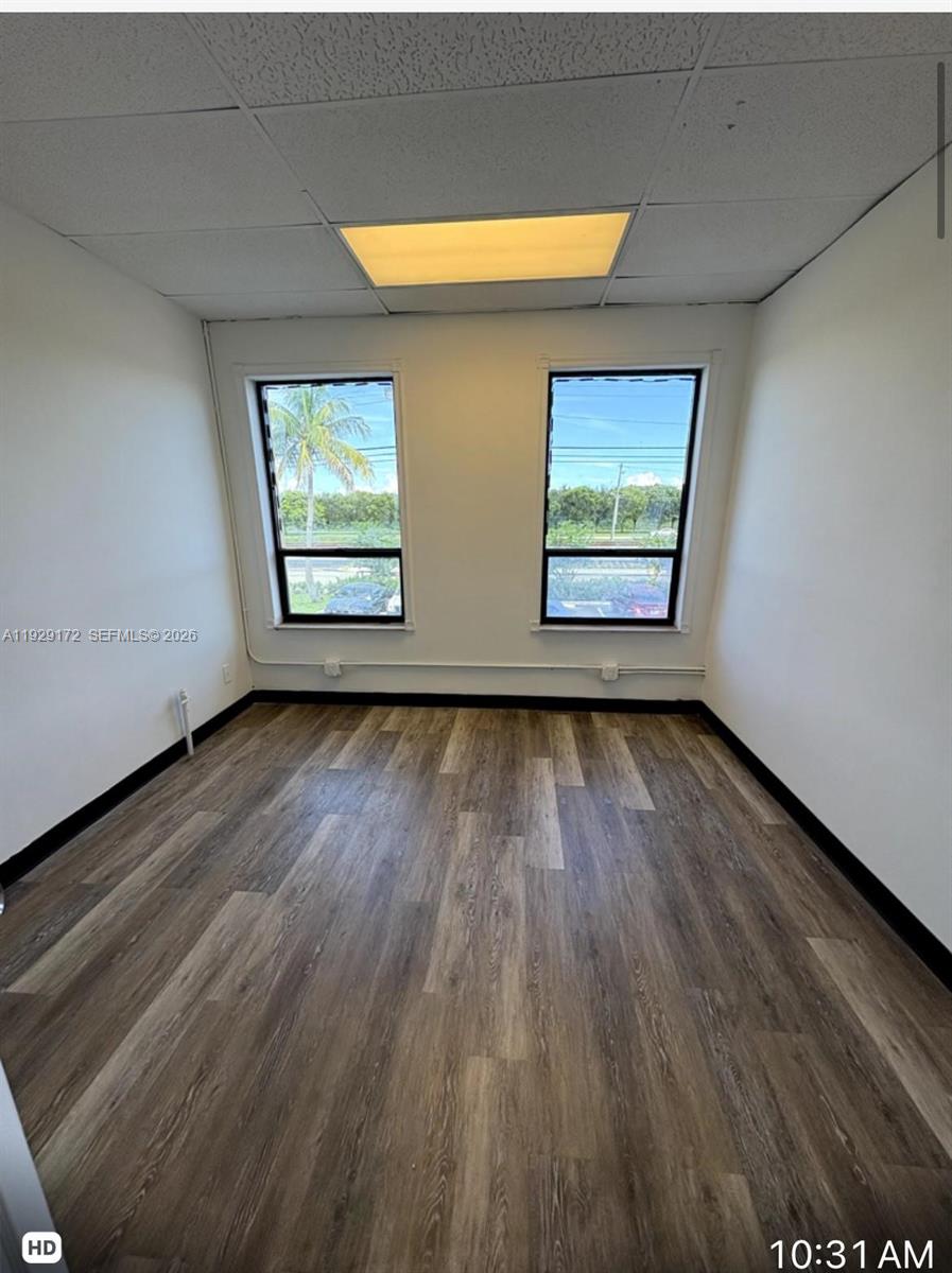 An empty office room features white walls, wood-look flooring, and two windows overlooking a parking lot — 2001 N Dixie Hwy # 4, Pompano Beach FL 33060, POMPANO BEACH, FL
