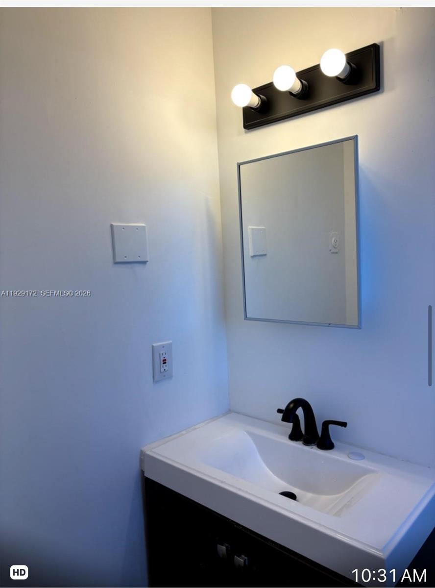A bathroom vanity features a white sink, black faucet, medicine cabinet, and three-light fixture — 2001 N Dixie Hwy # 4, Pompano Beach FL 33060, POMPANO BEACH, FL