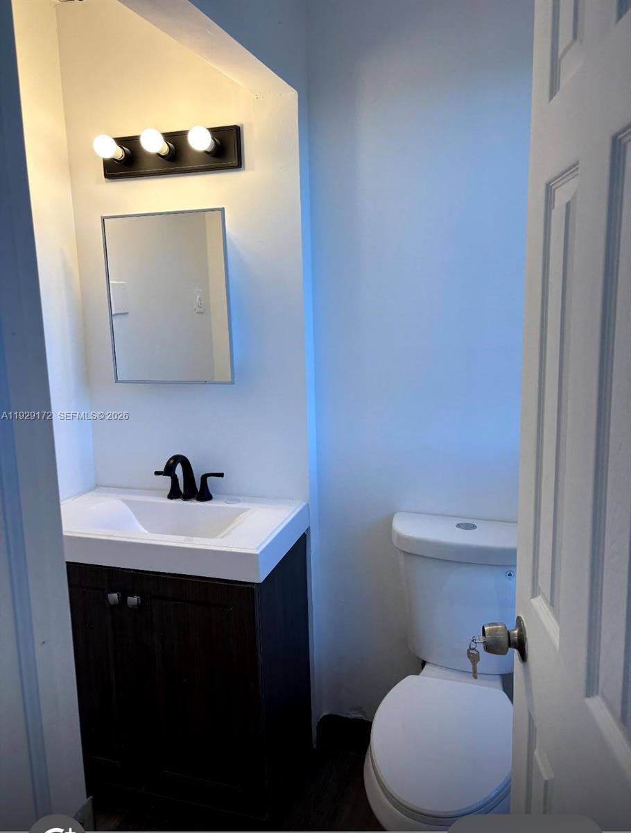 A small bathroom features a dark wood vanity, a white sink, and a white toilet — 2001 N Dixie Hwy # 4, Pompano Beach FL 33060, POMPANO BEACH, FL