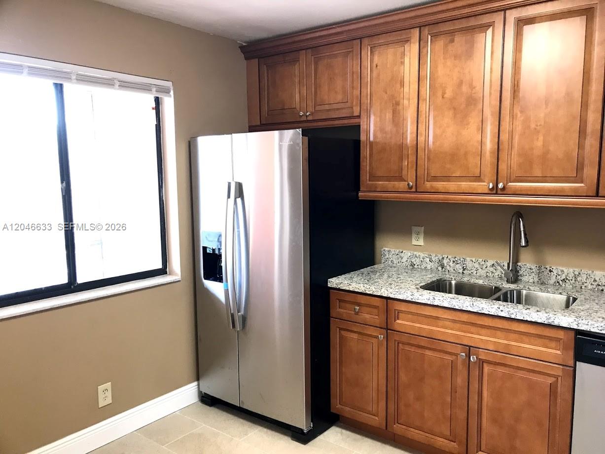A kitchen features wood cabinets, a stainless steel refrigerator, and a granite countertop with a sink — 369 Lakeview Dr # 203, Weston FL 33326, WESTON, FL