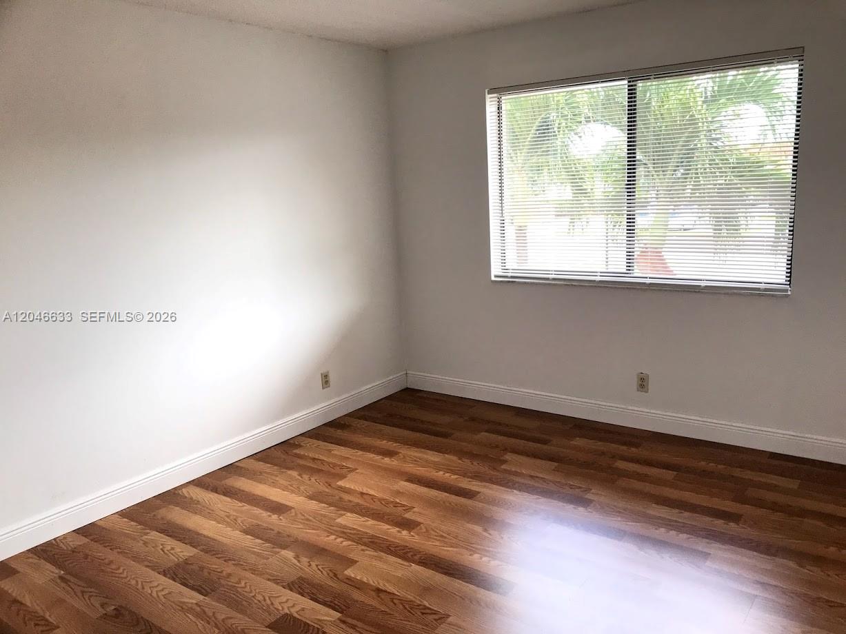 An empty bedroom features white walls, wood-look flooring, and a window with horizontal blinds — 369 Lakeview Dr # 203, Weston FL 33326, WESTON, FL