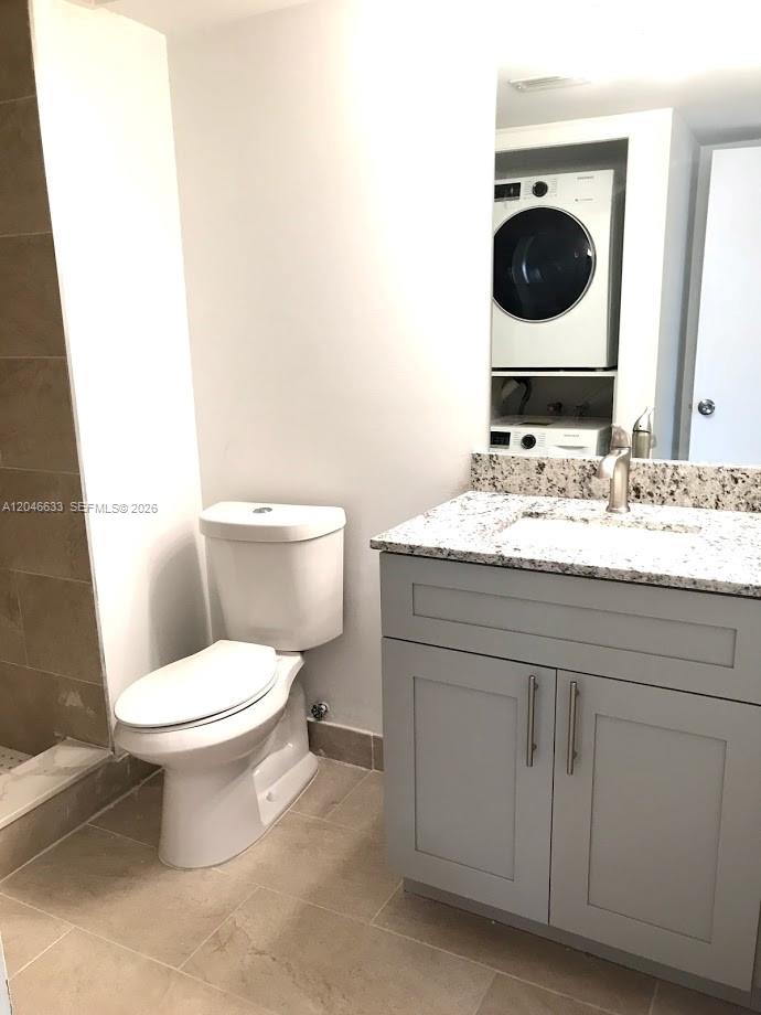A bathroom features a toilet, a gray vanity with a granite countertop, and stacked laundry — 369 Lakeview Dr # 203, Weston FL 33326, WESTON, FL