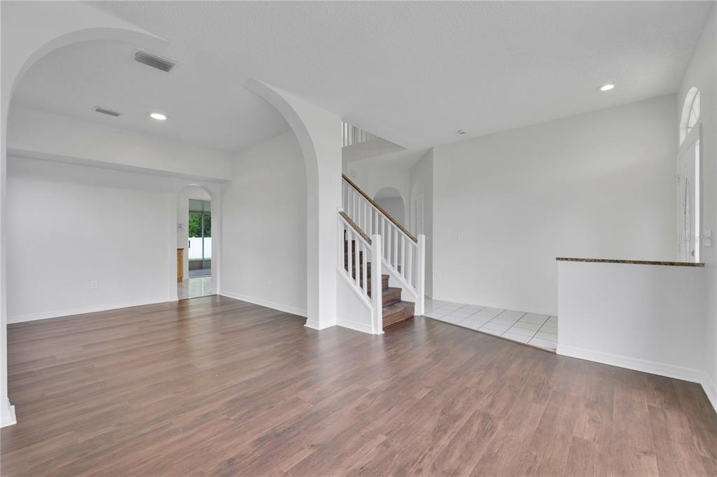 An interior view of a living area with wood flooring, arched doorways, and a staircase — 1101 BLUFIELD AVENUE, BRANDON, FL