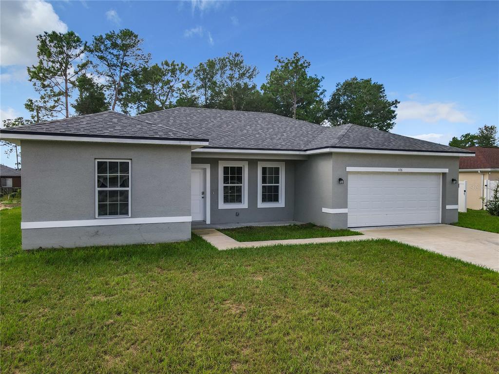 A single-story gray house with a white garage door and a shingled roof — 406 MARION OAKS TRAIL, OCALA, FL