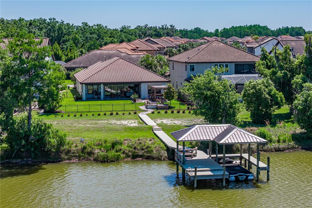 An aerial view of a waterfront house with a backyard, fence, and private boat dock — 6743 SUNSET VISTA WAY, LAND O LAKES, FL