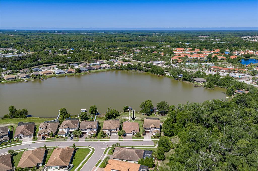 An aerial view shows a suburban neighborhood with houses situated along the edge of a lake — 6743 SUNSET VISTA WAY, LAND O LAKES, FL