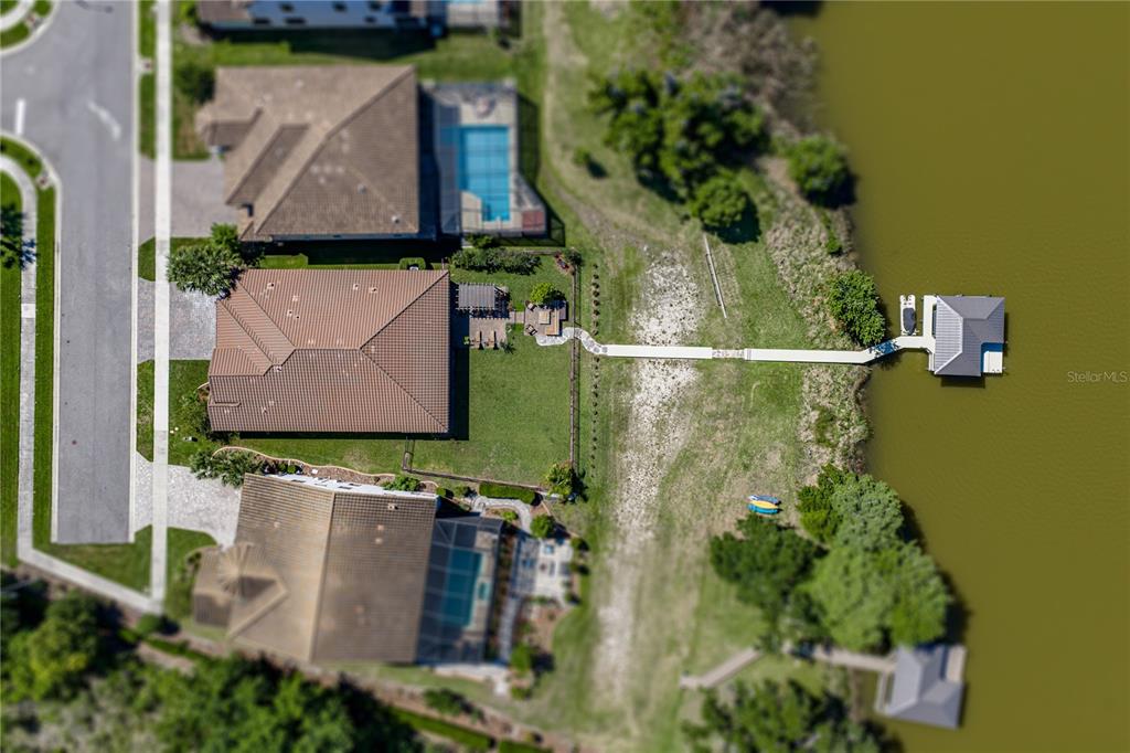 An aerial view shows houses with pools and a long dock extending into a lake — 6743 SUNSET VISTA WAY, LAND O LAKES, FL