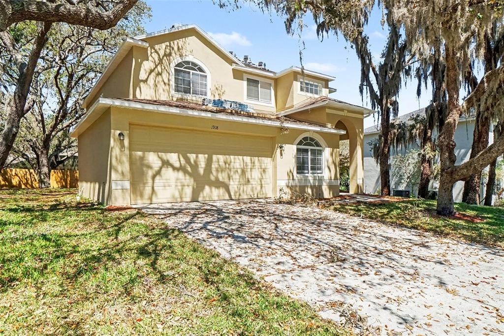 A two-story tan house with a two-car garage and a driveway covered in leaves — 1918 ASPENRIDGE COURT, OCOEE, FL
