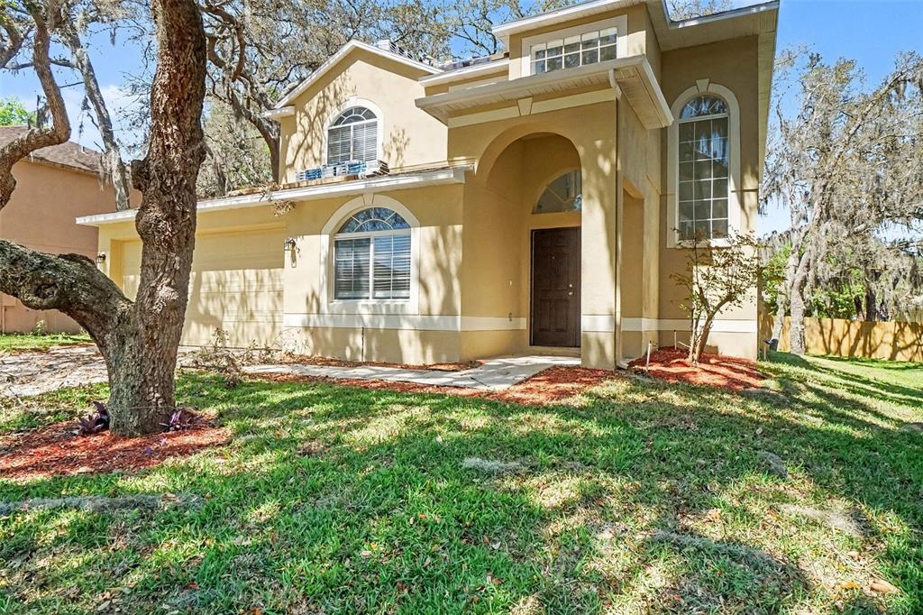 A two-story tan stucco house with a dark front door and a two-car garage — 1918 ASPENRIDGE COURT, OCOEE, FL