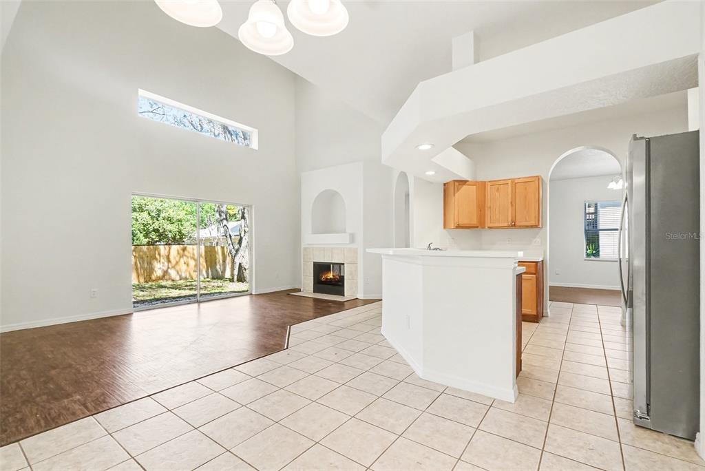 A living room with a fireplace and sliding glass doors adjacent to a tiled kitchen — 1918 ASPENRIDGE COURT, OCOEE, FL
