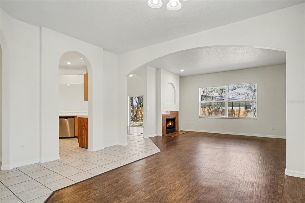 A living room with wood-look flooring, a fireplace, and an arched entryway to the kitchen — 1918 ASPENRIDGE COURT, OCOEE, FL