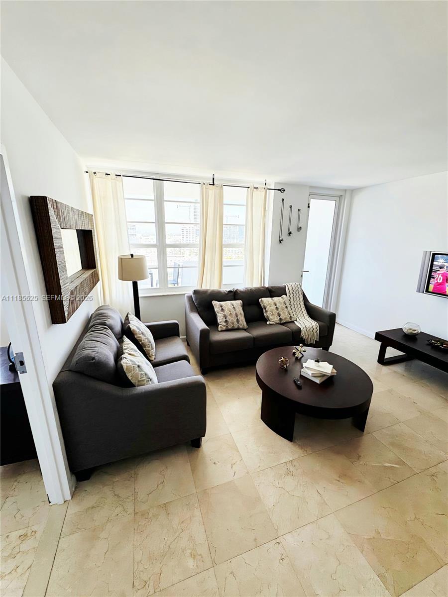 A living room features two dark gray sofas, a round coffee table, and tile flooring — 100 Lincoln Rd # 1243, Miami Beach FL 33139, MIAMI BEACH, FL