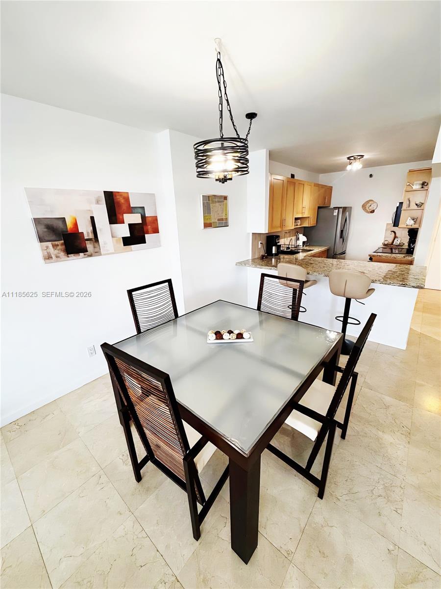 A dining area with a glass-topped table and chairs sits adjacent to an open kitchen — 100 Lincoln Rd # 1243, Miami Beach FL 33139, MIAMI BEACH, FL