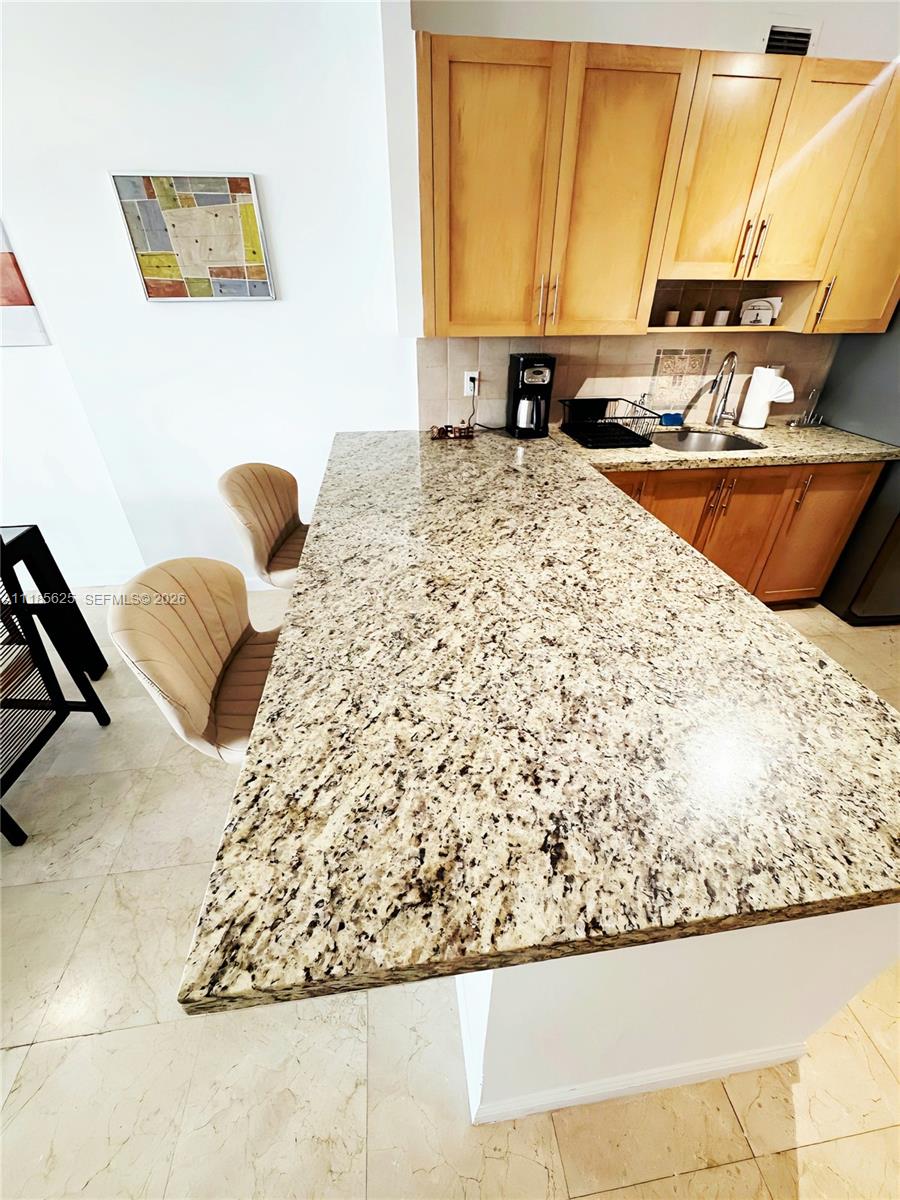 A kitchen features a granite breakfast bar, light wood cabinets, and two upholstered chairs — 100 Lincoln Rd # 1243, Miami Beach FL 33139, MIAMI BEACH, FL