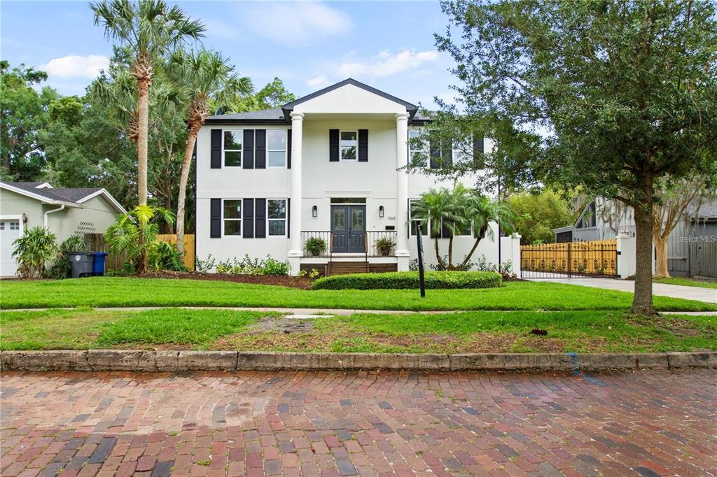 A two-story white house with black shutters and a front porch stands behind a lawn — 1368 HIBISCUS AVENUE, WINTER PARK, FL