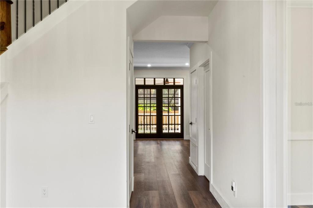 A hallway with wood-look flooring leads toward a set of dark-framed glass double doors — 1368 HIBISCUS AVENUE, WINTER PARK, FL