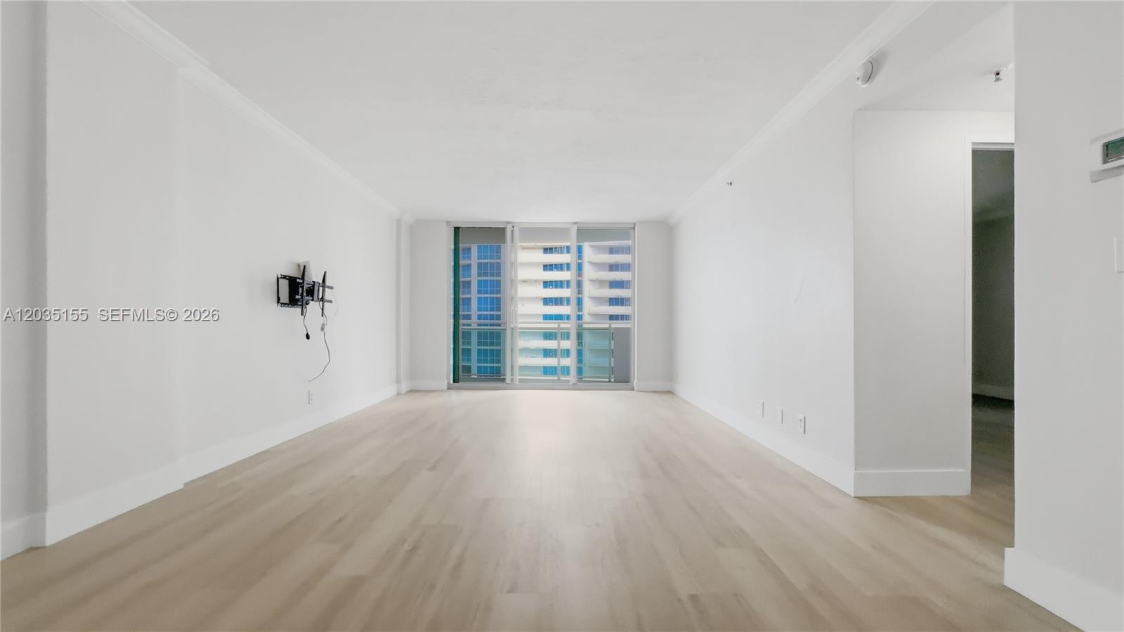 An empty room features light wood-look flooring, white walls, and a sliding glass door — 3001 S Ocean Dr # 1415, Hollywood FL 33019, HOLLYWOOD, FL