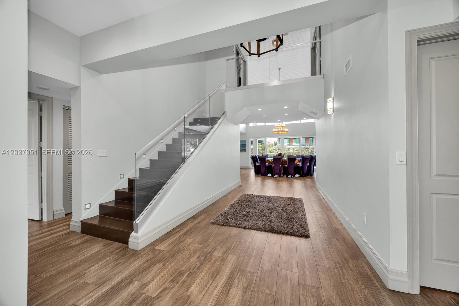 A bright entryway features wood-look flooring, a small bench, and a palm tree wall art — 1076 NE Little River Dr, Miami FL 33138, MIAMI, FL