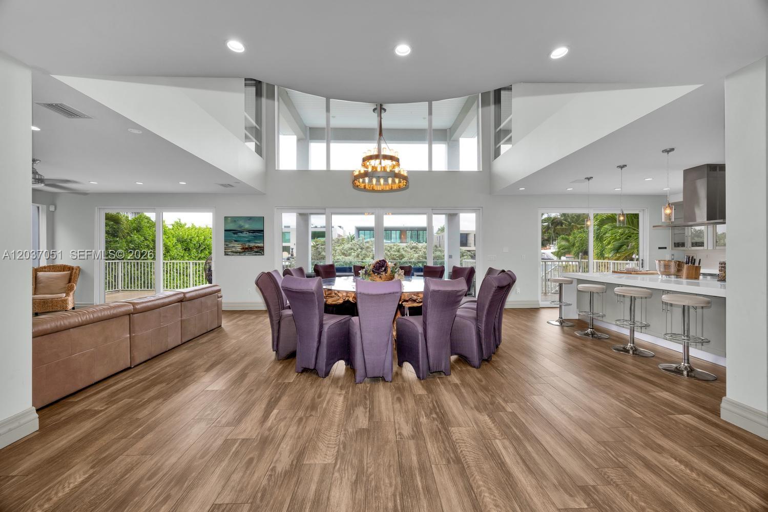 A modern foyer features a glass-railed staircase, wood flooring, and a view into the dining room — 1076 NE Little River Dr, Miami FL 33138, MIAMI, FL