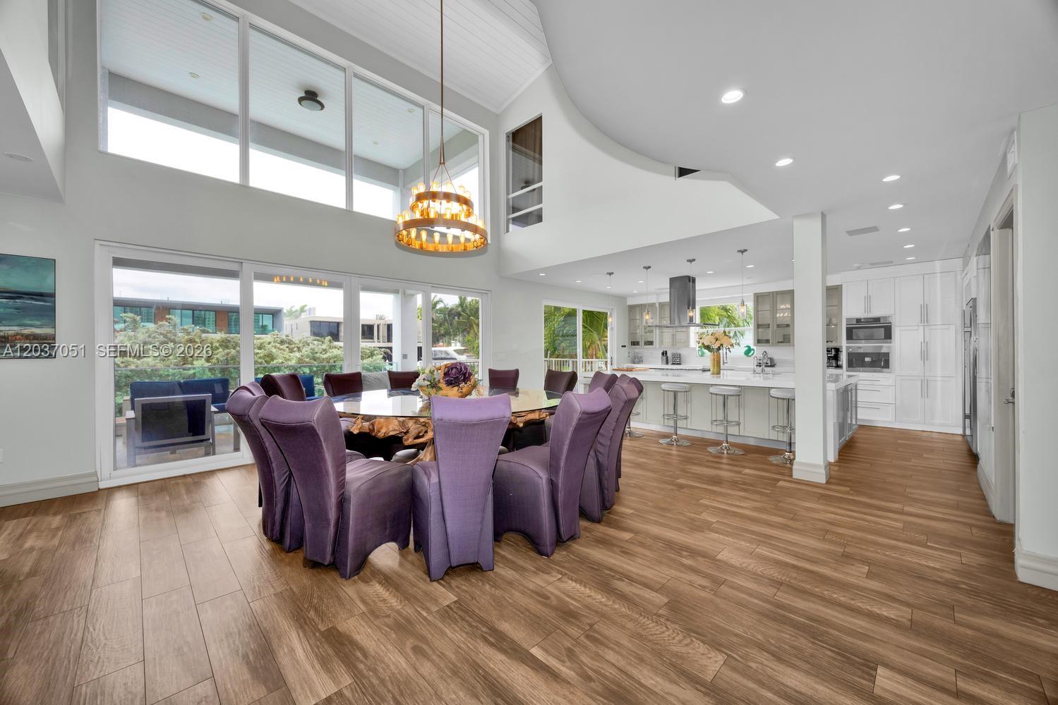 A spacious open-concept living and dining area features high ceilings, wood flooring, and large windows — 1076 NE Little River Dr, Miami FL 33138, MIAMI, FL